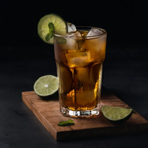 A long drink with lime and ice on a wooden board