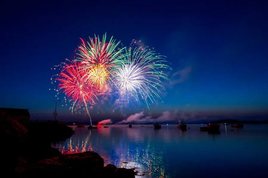 Fireworks over water in the blue of dusk