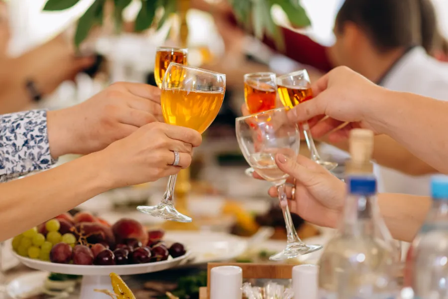Hands raising wine glasses over a laid table